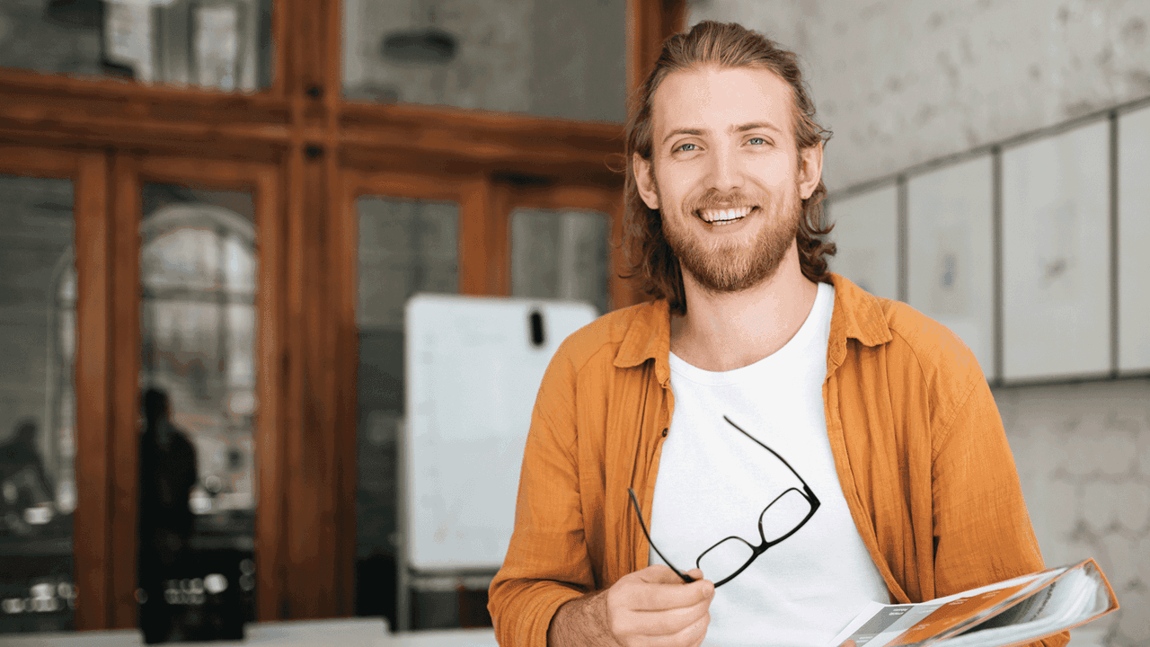 Nuori mies hymyilee ja katsoo kohti.