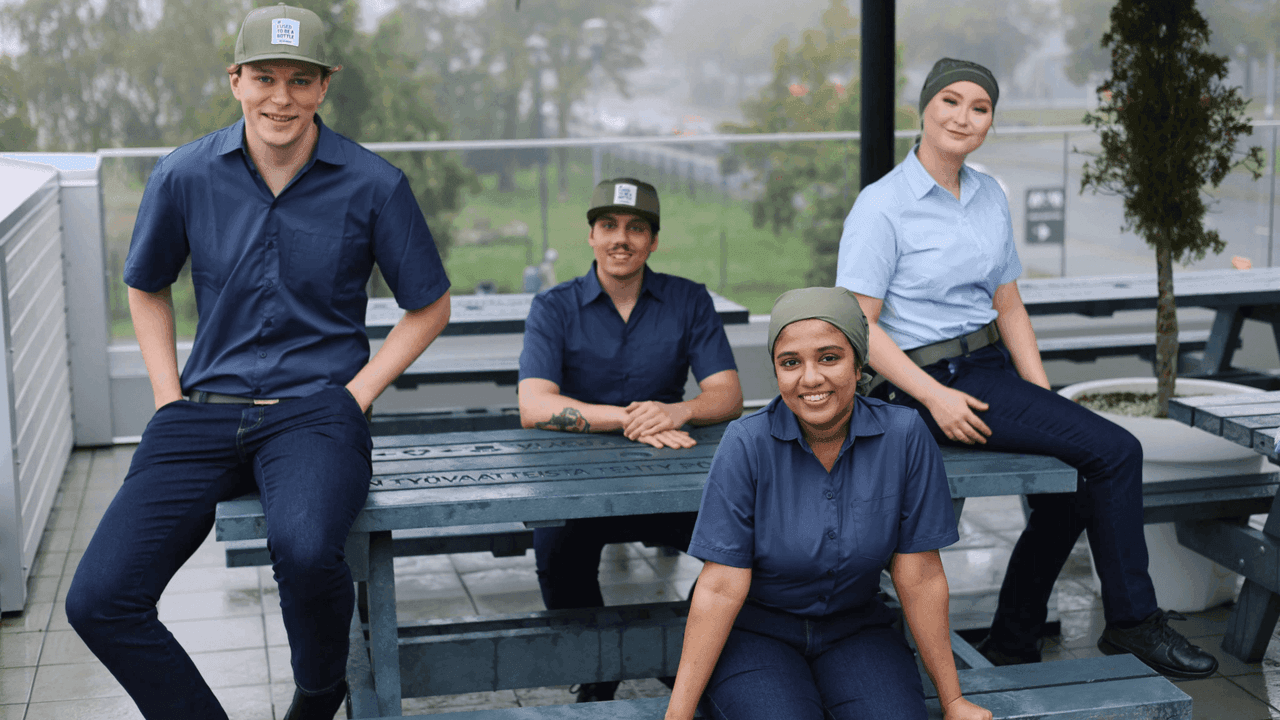 Hesburgerin työntekijät istuvat ulkona ja hymyilevät