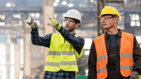 Kuvituskuvassa kaksi miestä keskustelee tehtaassa.